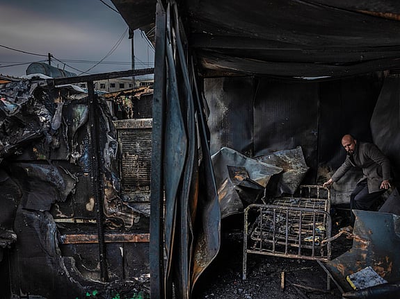 Man står intill säng i utbränt hus