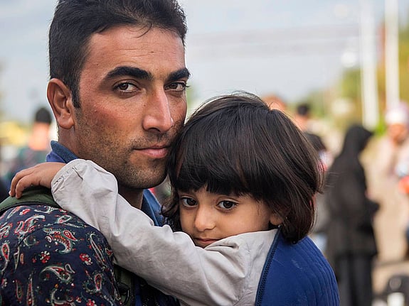 Man håller barn i famnen.