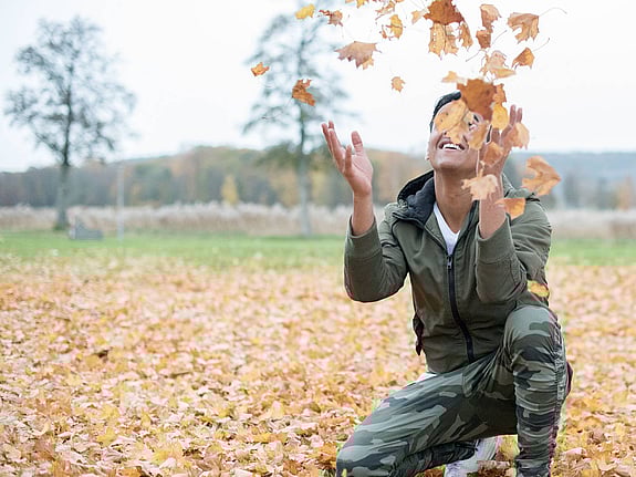 Pojke som kastar upp höstlöv i luften
