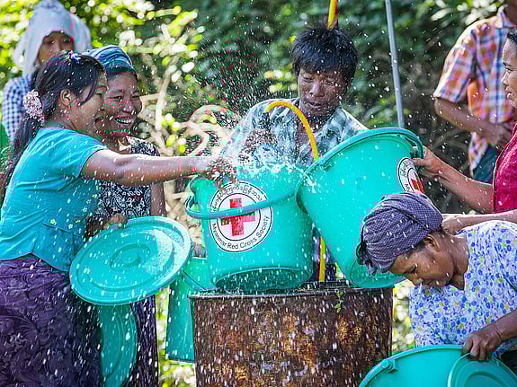 En grupp personer hämtar vatten ur brunn.