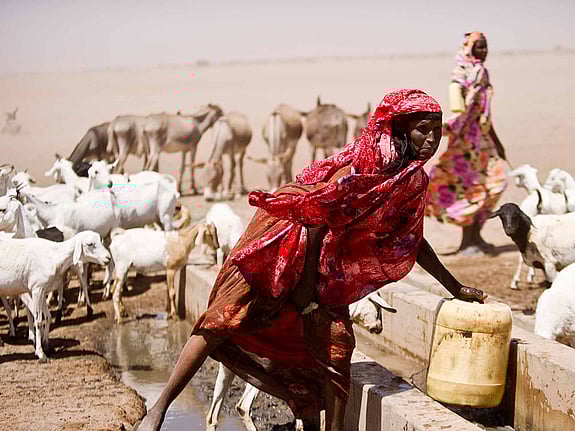 Rödklädd kvinna hämtar vatten vid torka i Kenya