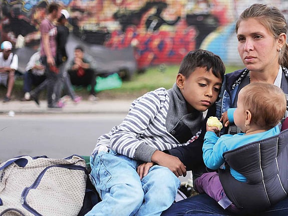 Mamma med barn sitter vid vägkant