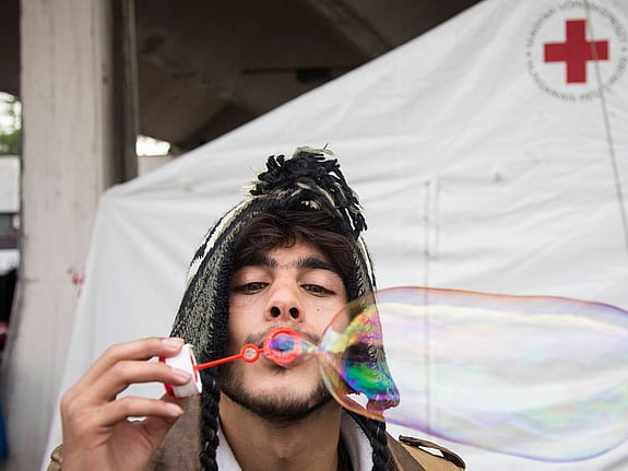 Man klädd i mössa blåser såpbubblor