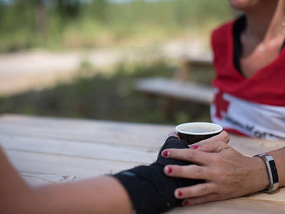 Stödjande hand på hand med kaffekopp