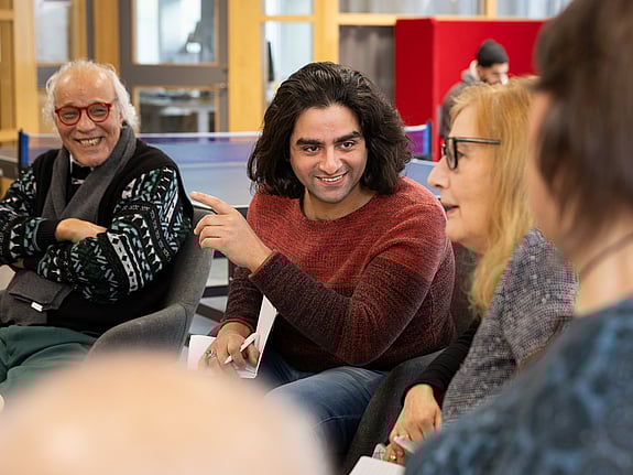 Personer i samtal, leeende och glada.