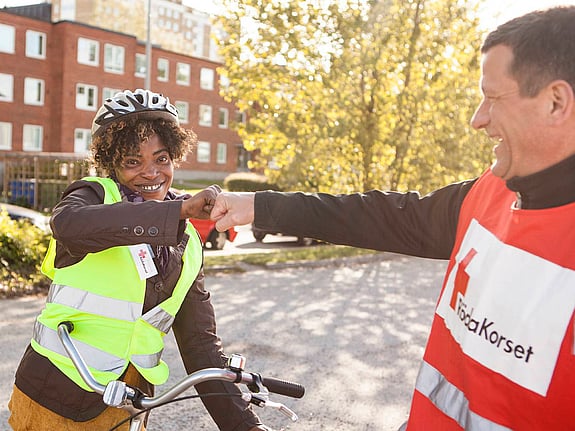 Rödakorsare hälsar på ungdom i cykelhjälm