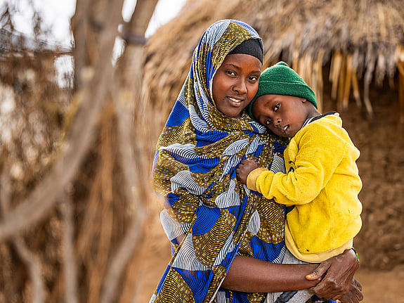 Kvinna håller sitt barn i famnen.
