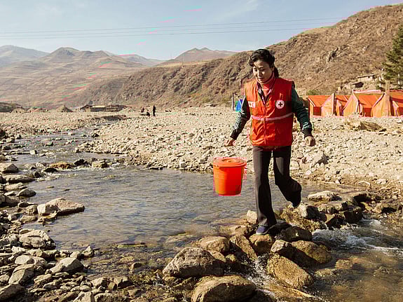 Röda Korsets volontär i Nordkorea går över vattendrag.