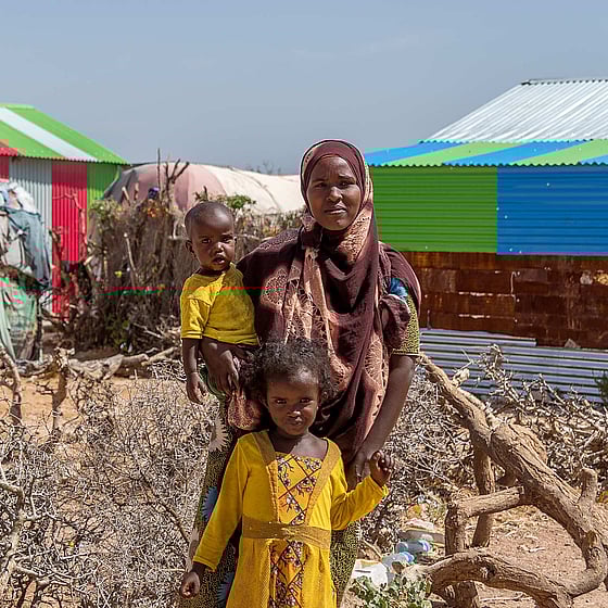 Mamma och barn framför tält.