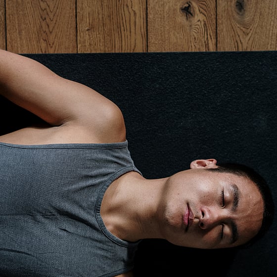 Man som ligger och gör andningsövningar efter fysisk aktivitet hemma