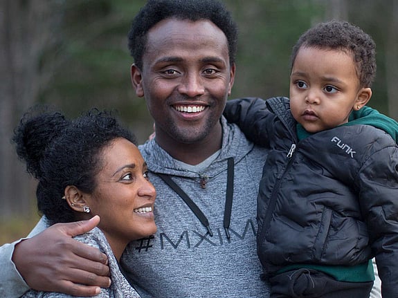 Leende man kramar kvinna och pojke