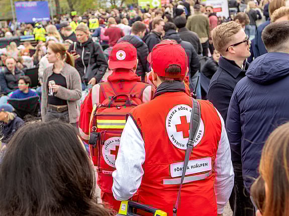 En person med röd väst och röd keps som rör sig i en folkmassa