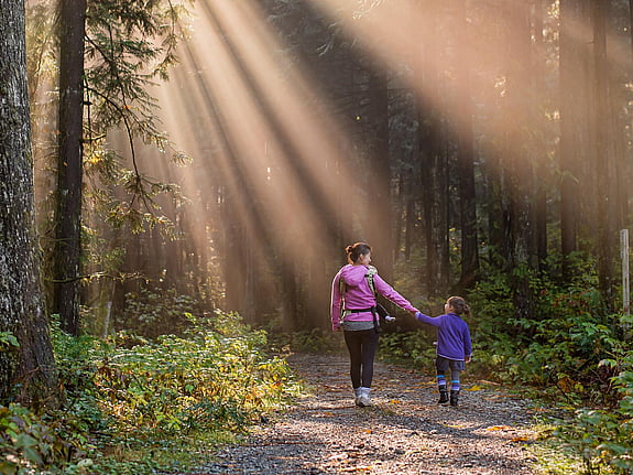 Kvinna och barn i solig skogsdunge