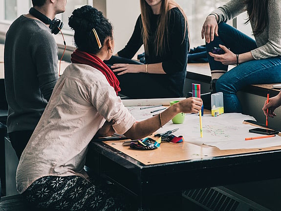 En lerfigur av ett barn med grön regnjacka i ett fönster.