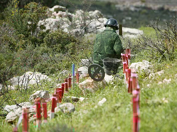 Minröjare arbetar i ett område förorenat av klustervapen.