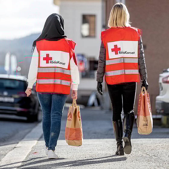 Två volontärer bär på matkassar