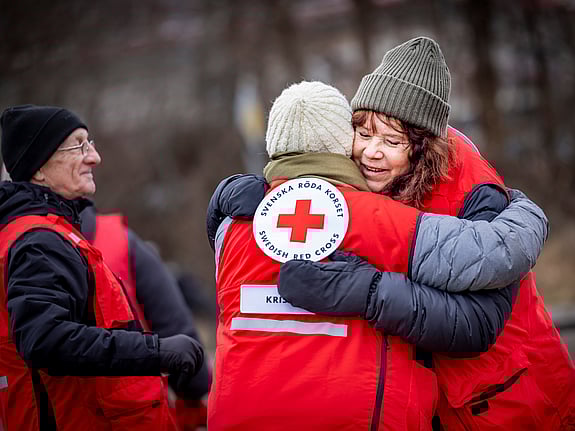 En person med röd väst och röd keps som rör sig i en folkmassa