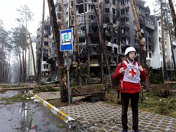 Barn kramar om sin mamma, i bakgrunden ser vi ruiner och en röda kors-bil.