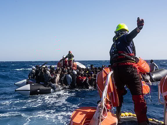Röda Korset volontärer hjälper hjälper människor i gummiflottar.