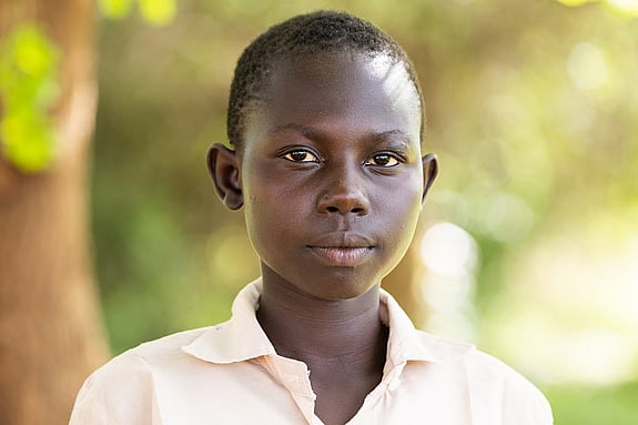 Jessica Lokidor står utomhus och tittar in i kameran, bakom henne finns ett träd med gröna löv.