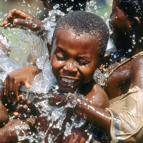 Barn som skvätter vatten på varandra.