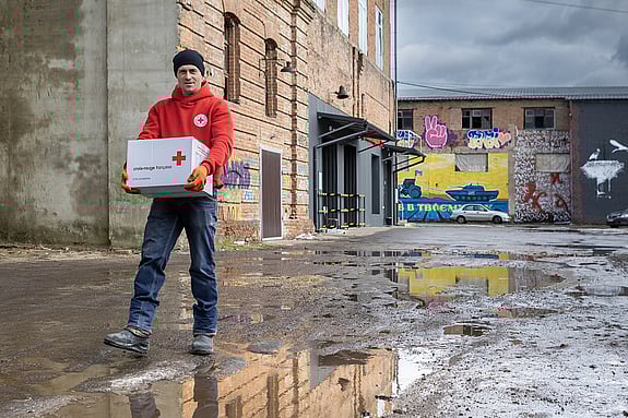 Volontären Serhii Hlushkov går med en låda märkt med Röda Korsets logotyp.