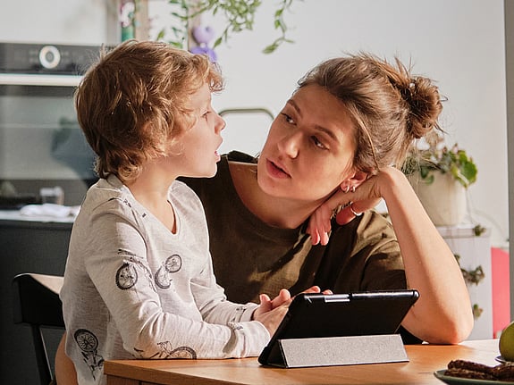 En lerfigur av ett barn med grön regnjacka i ett fönster.