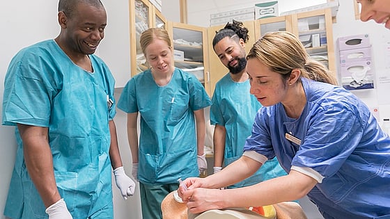 Män och kvinnor iklädda blå vårdkläder