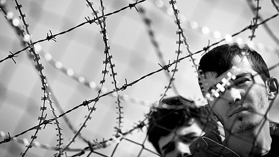 Två personers ansikten bakom taggtråd