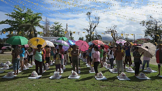 Flera personer under färgglada paraplyer och vimplar