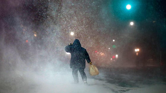 Man är ute och går i en snöstorm