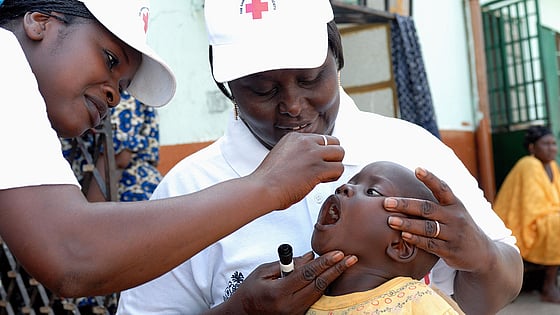 Volontär ger poliovaccin till barn