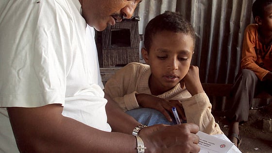 Ett barn får hjälp att skriva ett Rödakorsmeddelande.