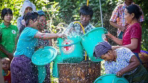 En grupp personer hämtar vatten ur brunn.