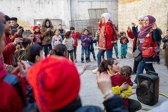 Barn leker tillsammans volontärer i Syrien.