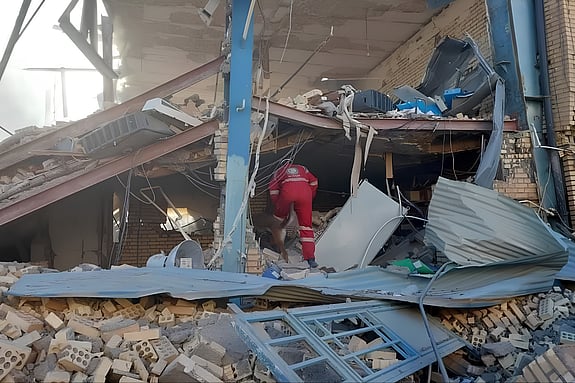 Volontär söker efter överlevande i en byggnad som har rasat i Iran