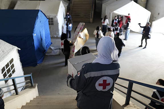 Kvinna som bär en kartong i flyktingboendet i Beirut