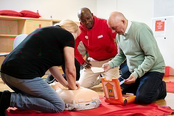 Tre personer arbetar med HLR på en docka.