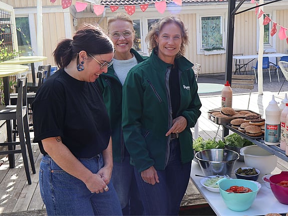 Cecilia Turemark, Madeleine Åman och Agneta Weimarsson från Parkering Malmö står uppradade på uteplatsen på röda korsets hus. I bild syns grönsaksbuffé till hamburgare.