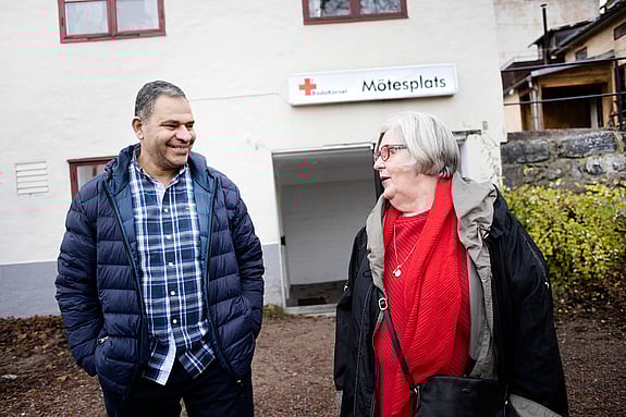 Syrisk man ler intill Röda Korset-volontär.