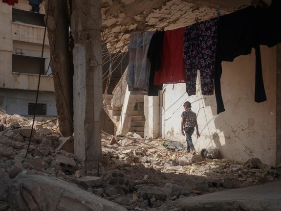 Syrisk pojke går bland rasade byggnader