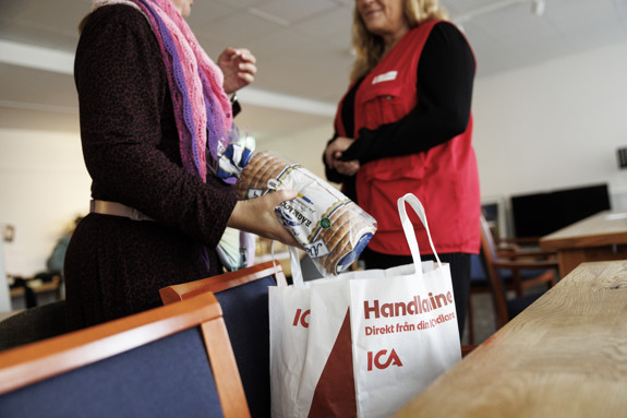 Två personer samtalar och i förgrunden syns en matkasse.