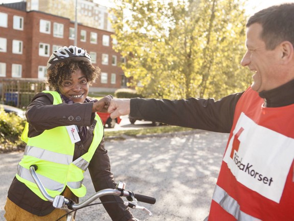 Rödakorsare hälsar på ungdom i cykelhjälm