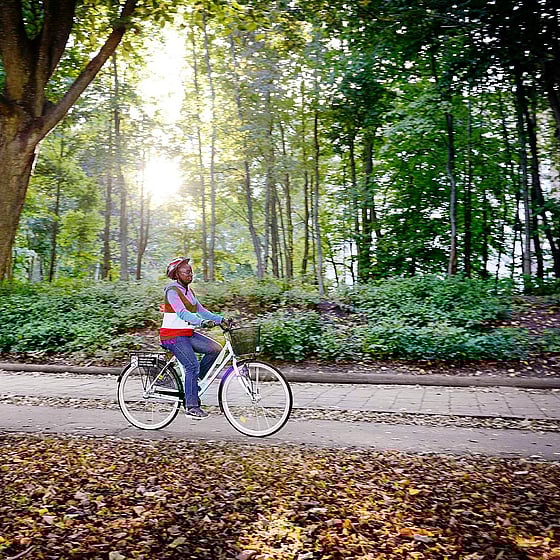 Kvinna cyklar på skogsväg