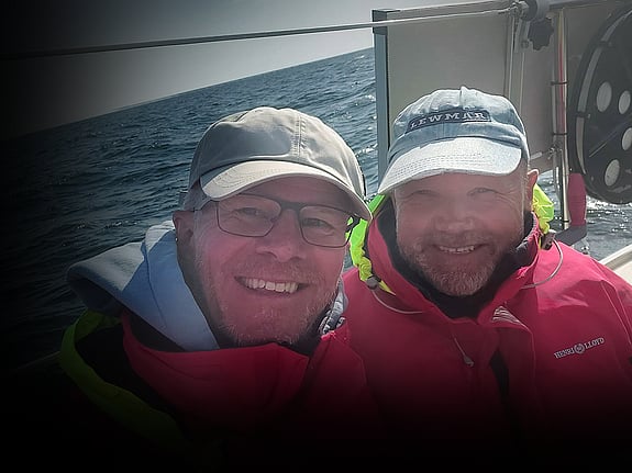 Två barn tittar fram bakom dörr och ser in i kameran med lekfull uppsyn.