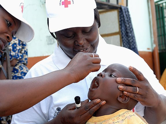Volontär ger poliovaccin till barn