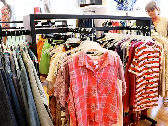Syntolkning: En volontär hänger upp kläder i en second hand-butik.