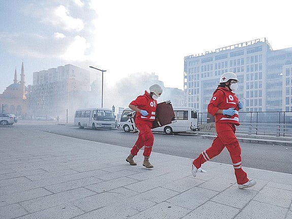 Två rödklädda personer springer med rök i bakgrunden