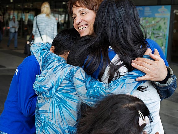 Lycklig kvinna kramar fyra barn