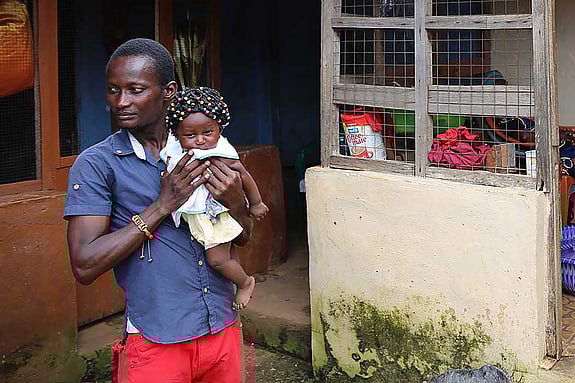 En man bär sin dotter efter jordskred i Sierra Leone.